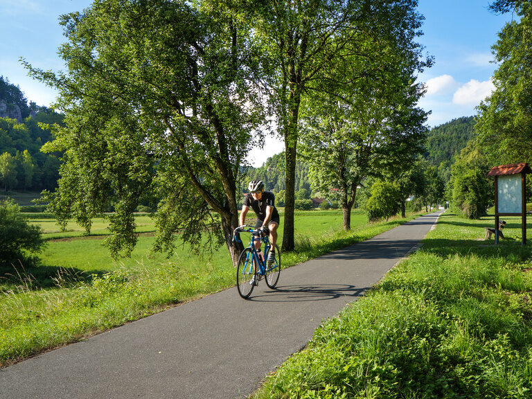 Eine Person radelt auf einem Pfad im Grünen in der Nähe des Landhaus Sponsel-Regus.