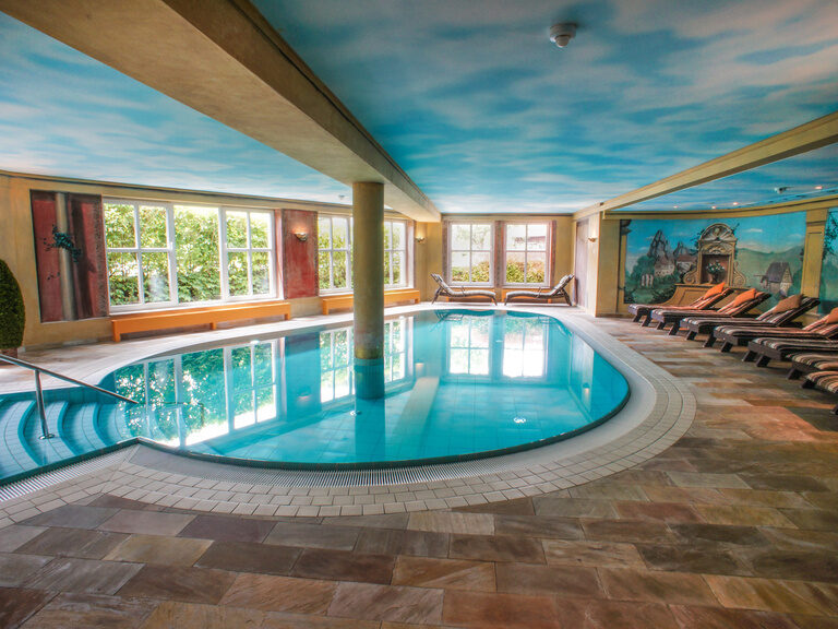 Ein luxuriöser Innenpool mit einem gemalten Himmelsmotiv an der Decke.