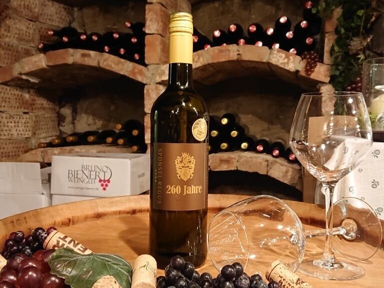 Eine Weinflasche steht auf einem Fass im Weinkeller im Landhaus Sponsel-Regus