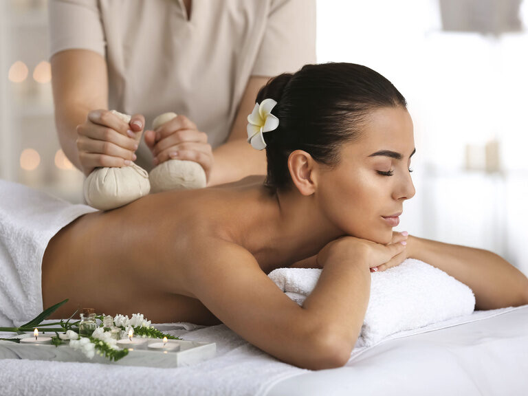 Eine Frau genießt eine entspannende Rückenmassage im WaldSpa des Hotels Sponsel-Regus in Franken und fühlt sich glücklich.